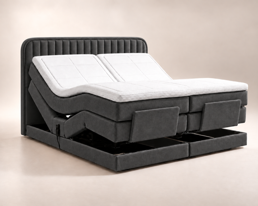 Antraciet elektrische boxspring met afgerond hoofdbord met verticale banen, witte topper en beide bedhelften omhoog versteld.