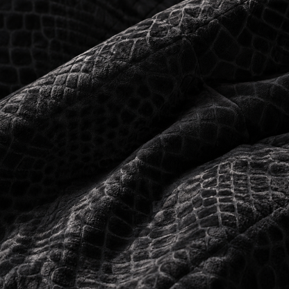 Extreme close-up van zwart velvet dekbed zonder overtrek met diepzwart reliëf slangenpatroon en zachte stofstructuur