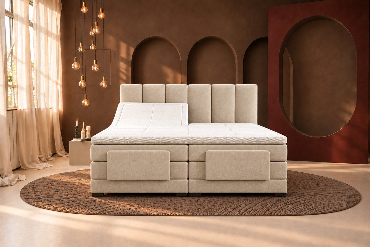Beige elektrische boxspring met verticaal gestoffeerd hoofdbord en verhoogd linker ruggedeelte in een warm verlichte slaapkamer.